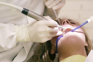 Gros plan d'une procédure dentaire avec des outils dans un cadre clinique, patient en cours de traitement.