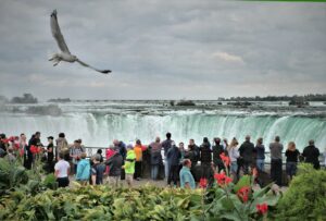 des gens prenant des photos de cascades sous un ciel nuageux